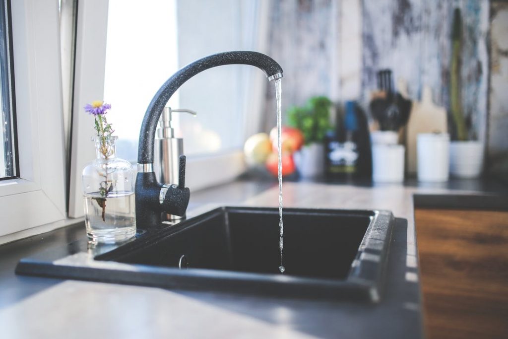 A black kitchen tap rushing water after fixing