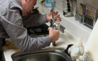 A Plumber fixing a kitchen tap